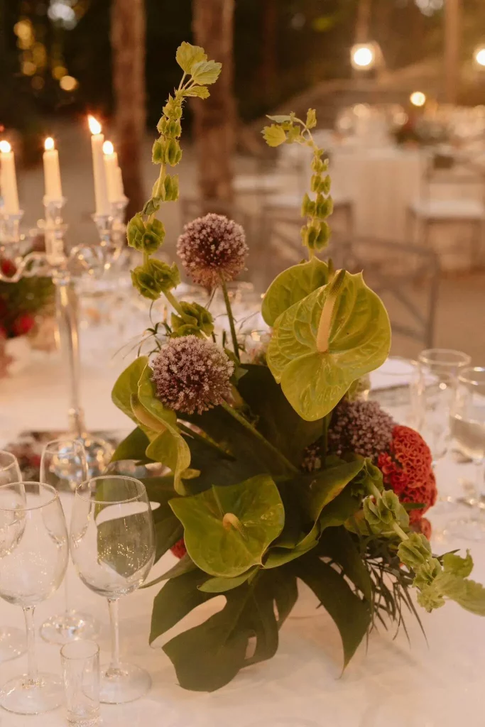 Centro de mesa para boda con flores tropicales y velas, diseño floral elegante con anthurium y allium