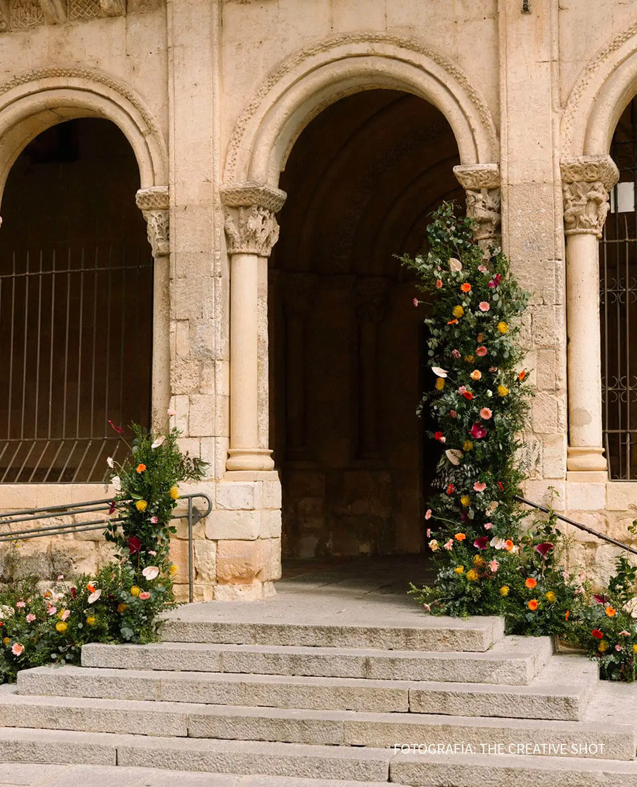 Decoración floral en iglesia románica con arco de entrada enmarcado por flores naturales para boda religiosa