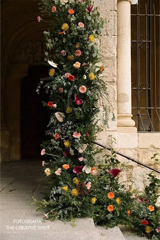 Decoración vertical de flores para bodas con gerberas, anturios, craspedias y verdes ornamentales en entrada
