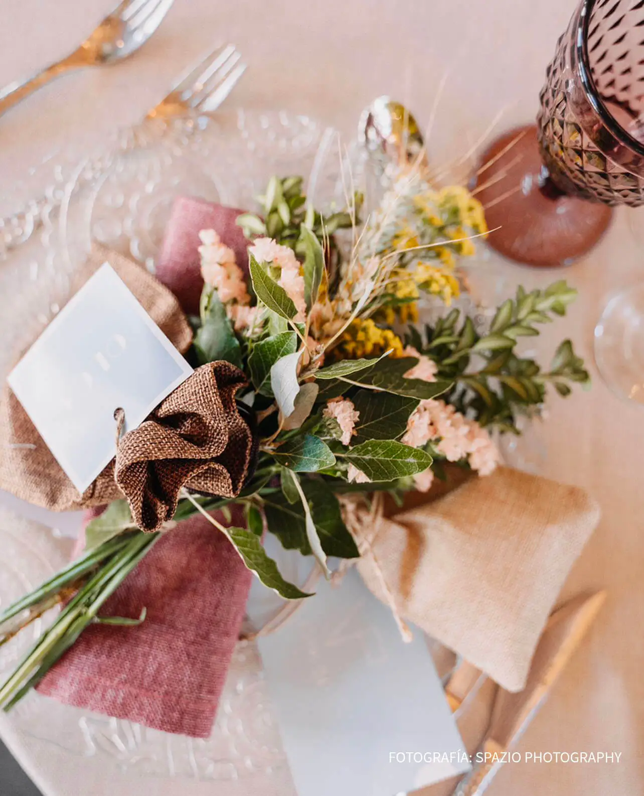 Detalle de centro de mesa para boda con mini ramo natural, servilleta de lino y vajilla de cristal tallado